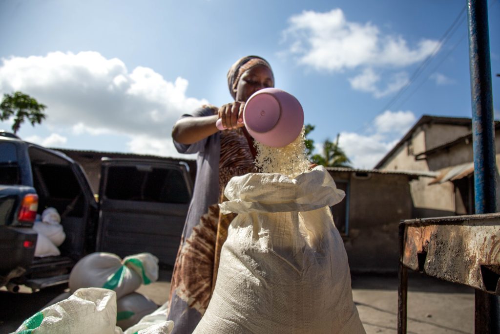 Woman pouring milled rice grains into a sack as part of small-scale rice trading, Tanzania